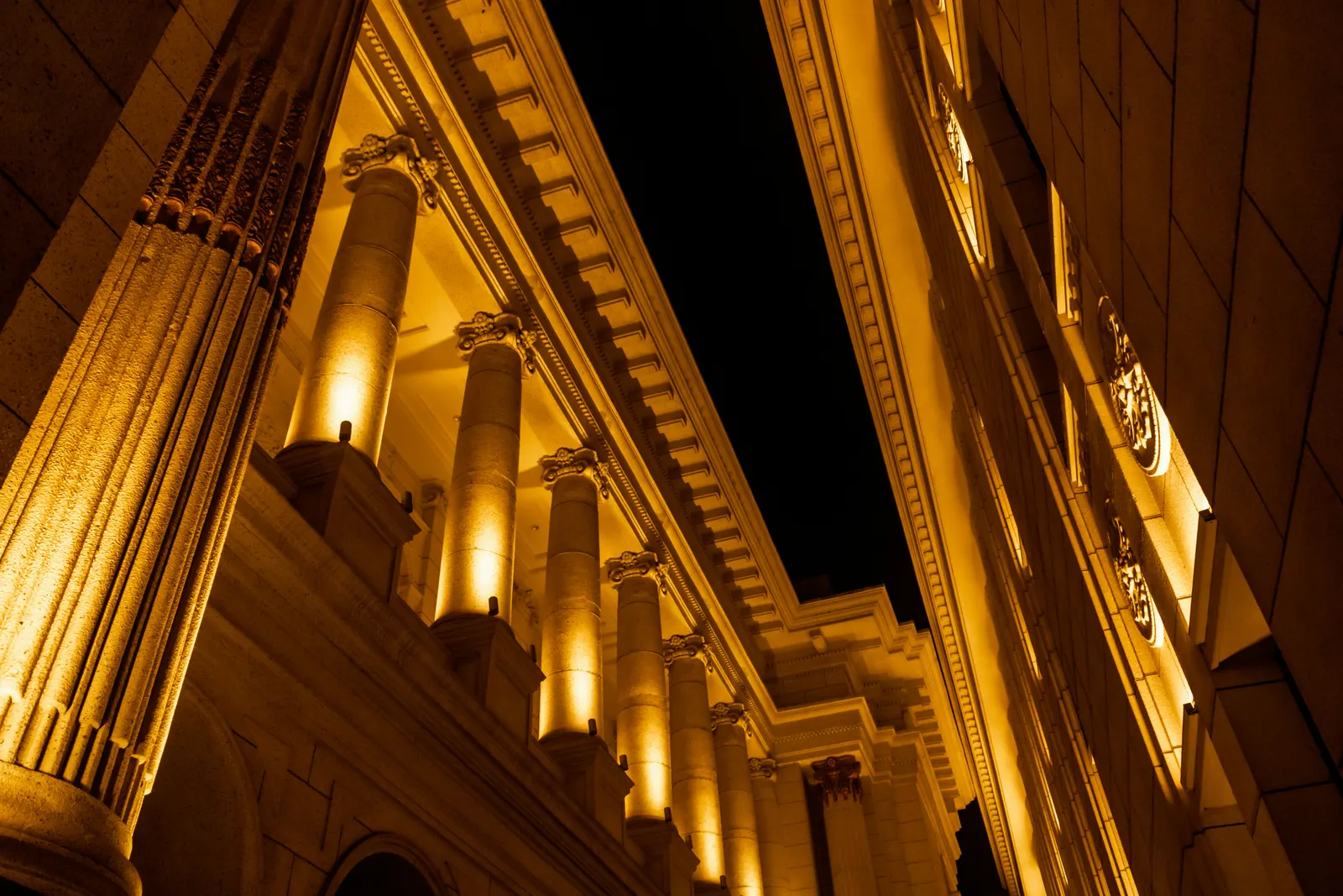 Stone columns uplit with warm narrow-beam facade lighting at night
