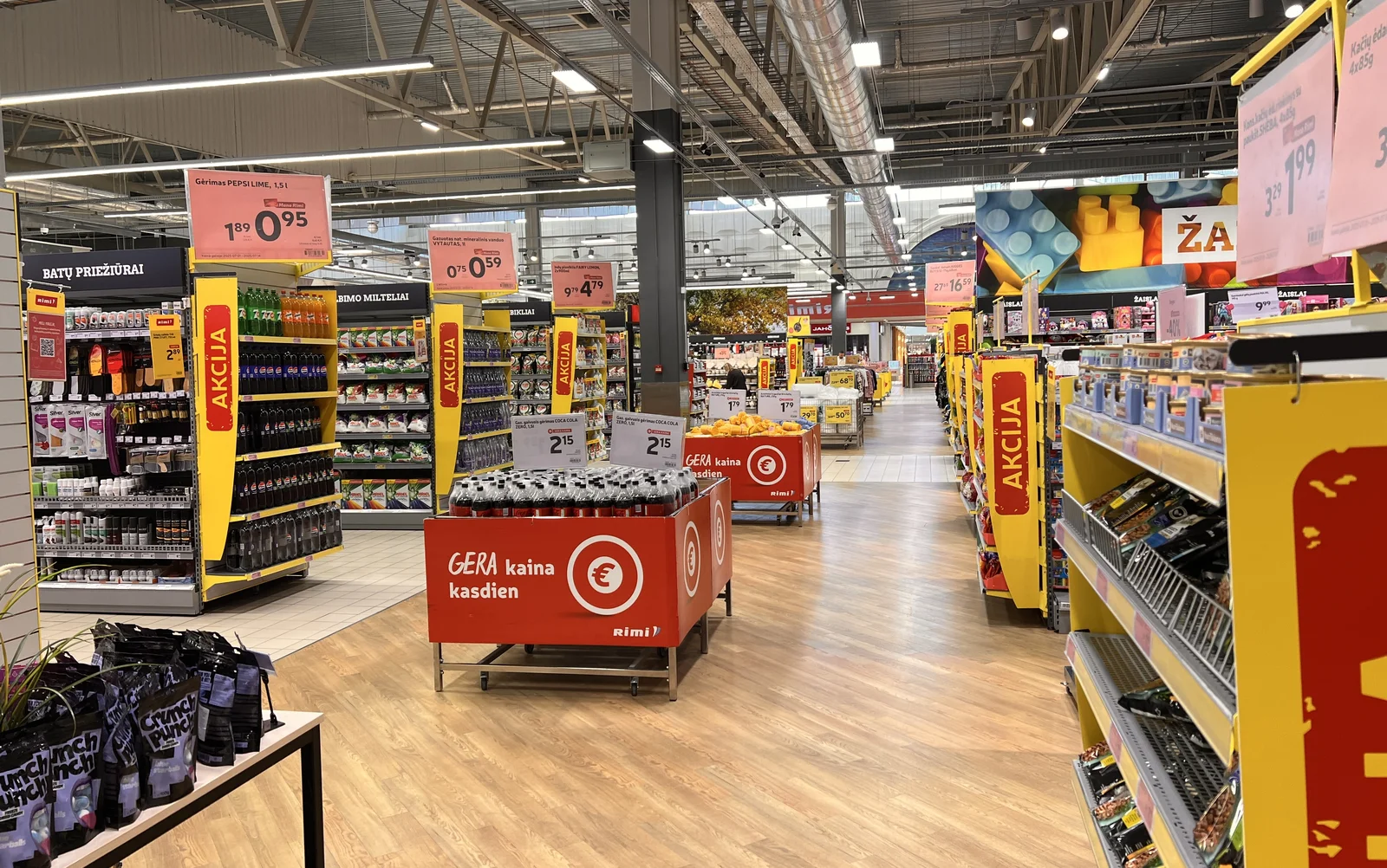 Supermarket aisle with shelves lit evenly from long ceiling light runs