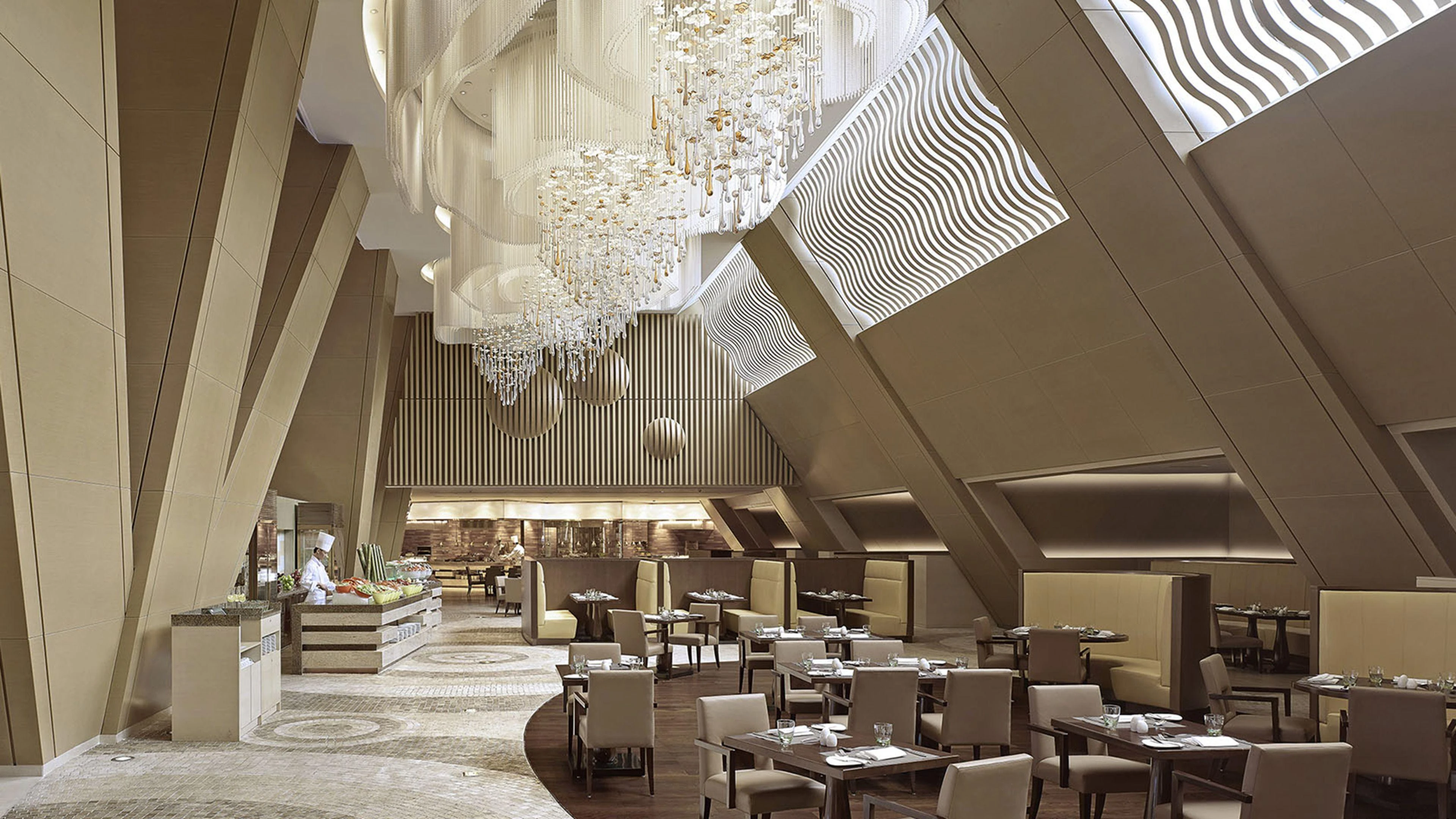 Hotel atrium with crystal chandelier cascades above an all-day dining restaurant