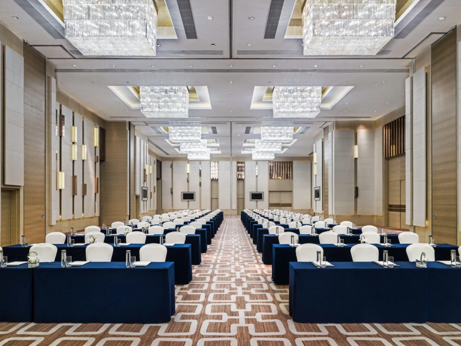 Hotel ballroom set for a conference under rows of square crystal chandeliers