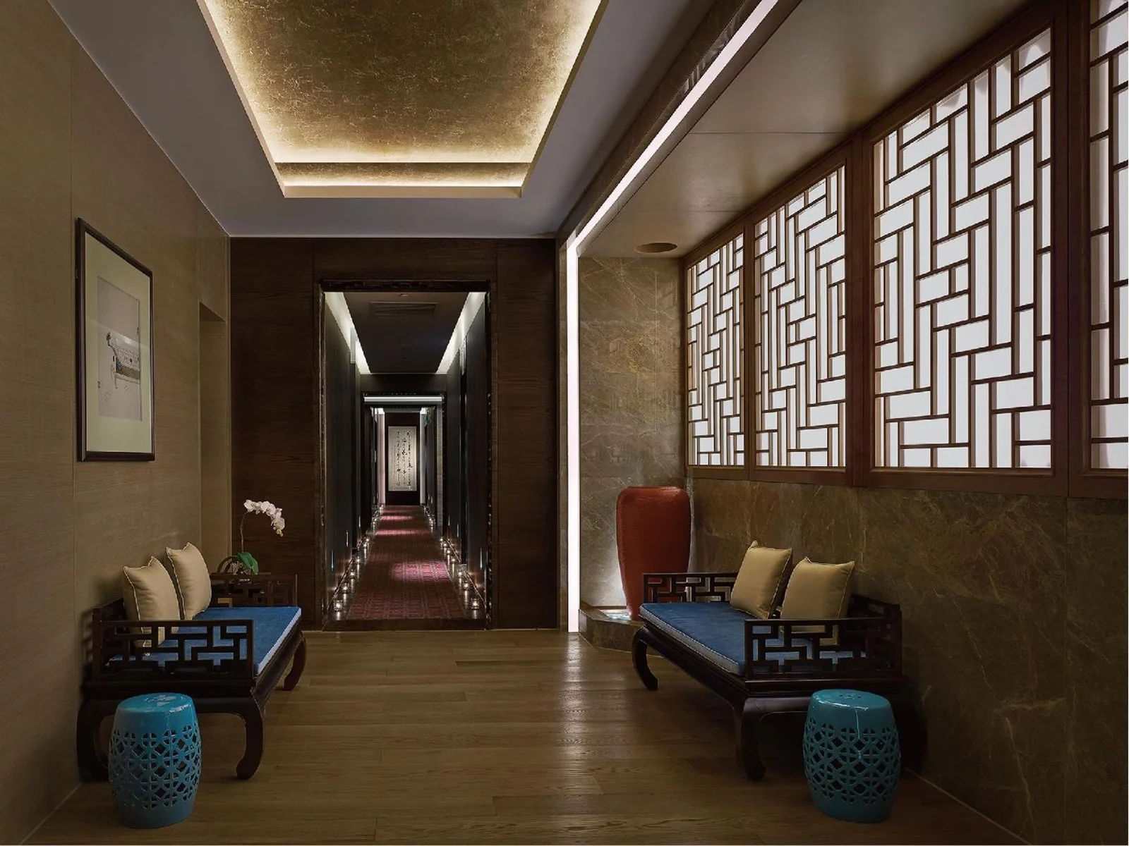 Hotel corridor with warm cove lighting and lit timber lattice screens