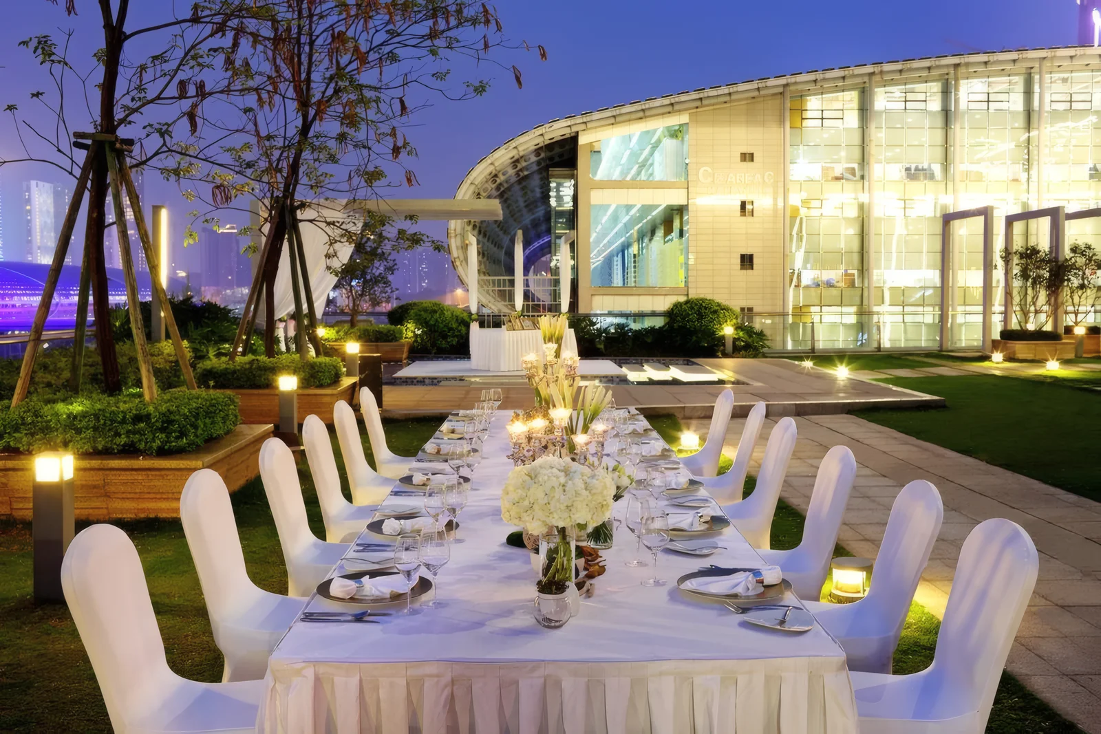 Hotel garden set for an evening dinner with bollard lights and a lit glass pavilion