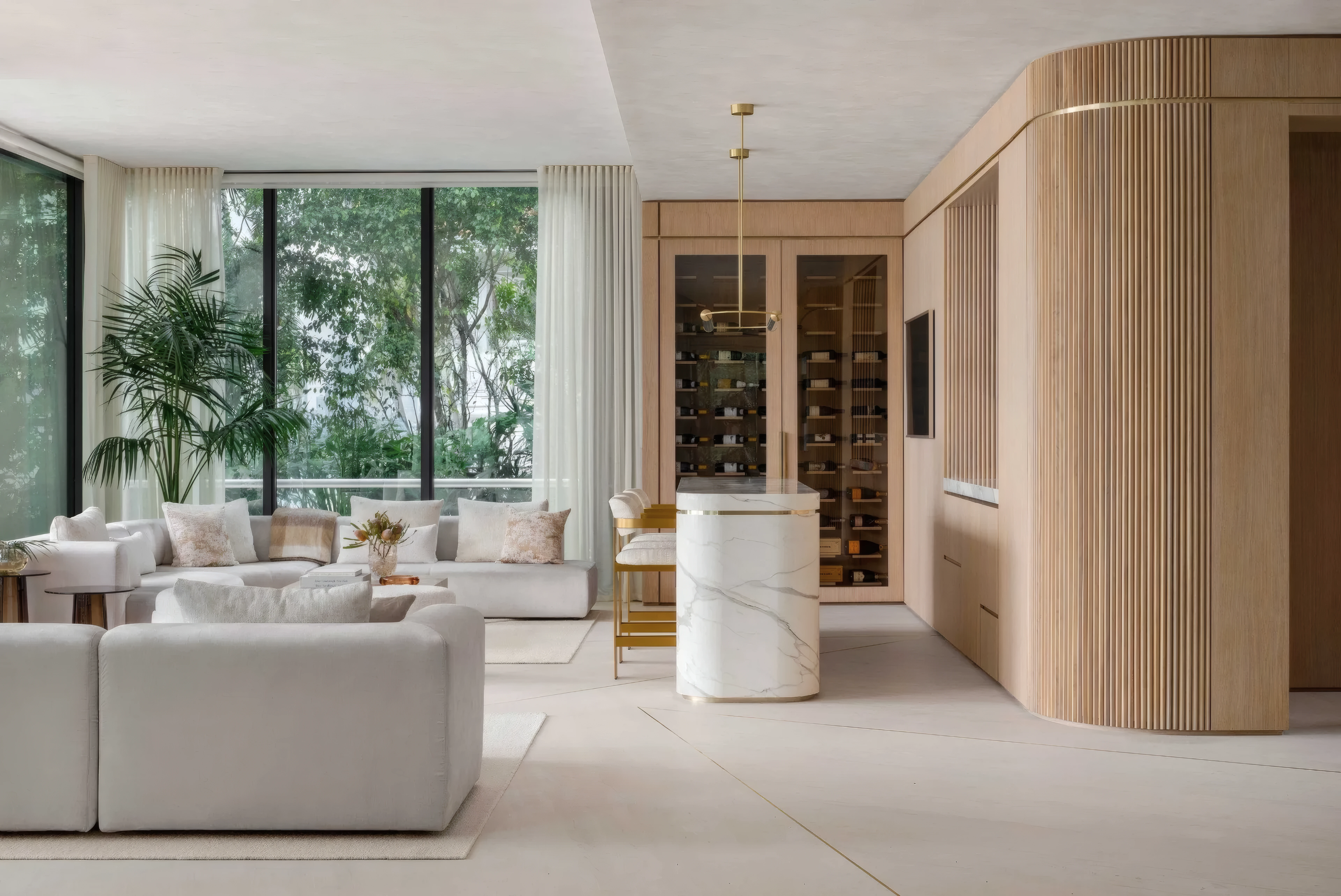 Brass pendant light over a marble kitchen island beside a wine wall