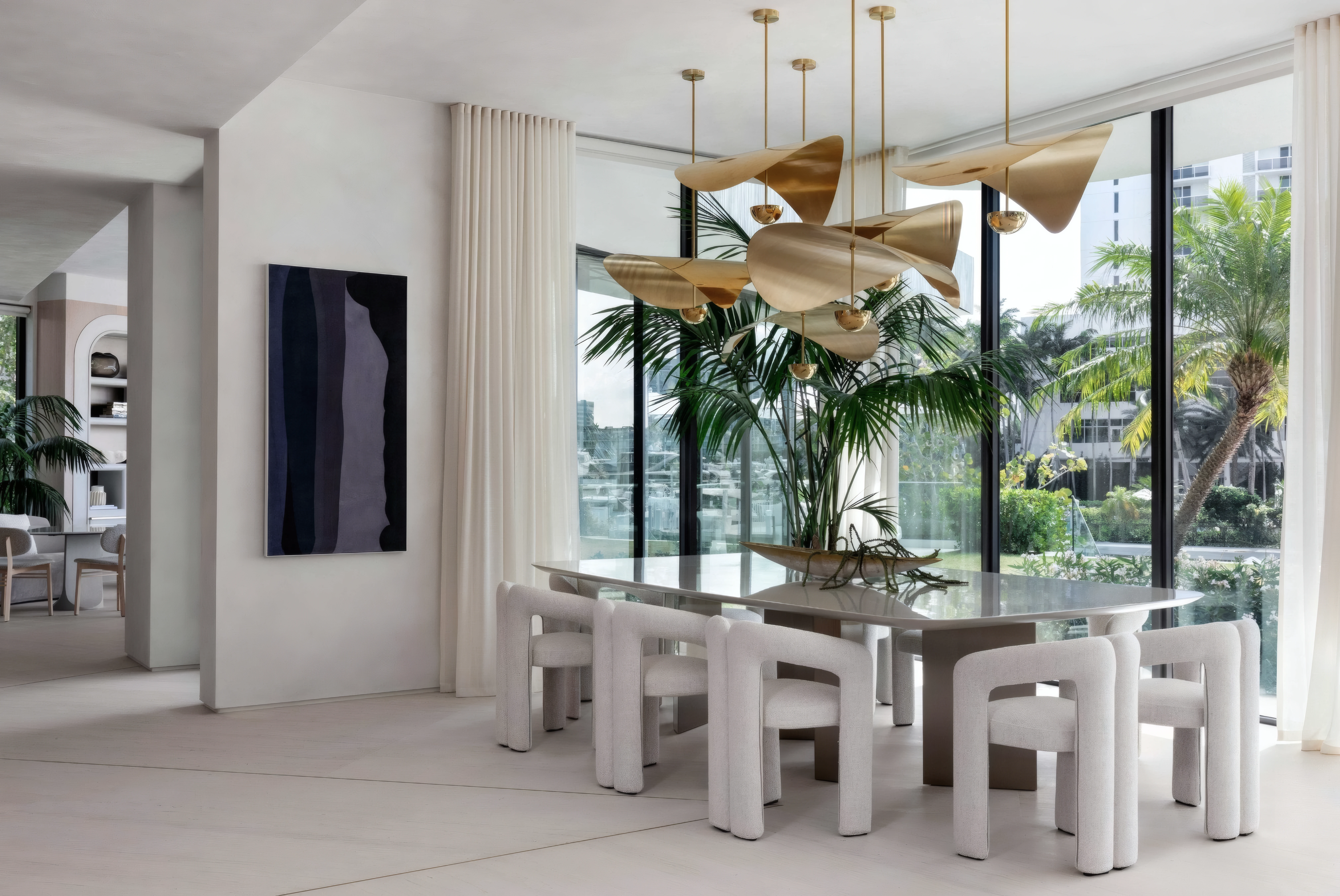 Dining room styled with a sculptural gold folded-fan pendant chandelier cluster over the table