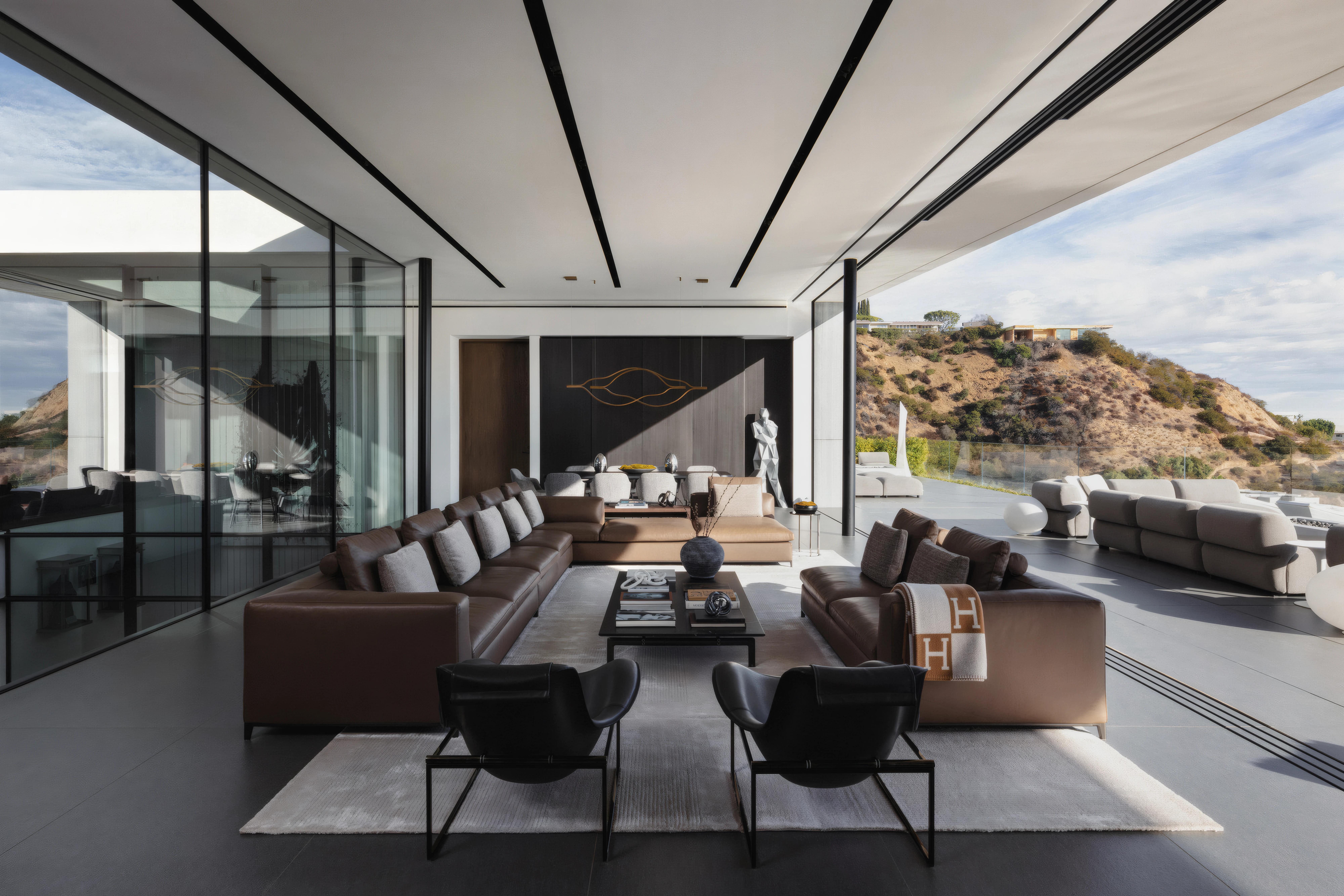 Linear LED lines recessed into a ceiling above an open living room with a mountain view