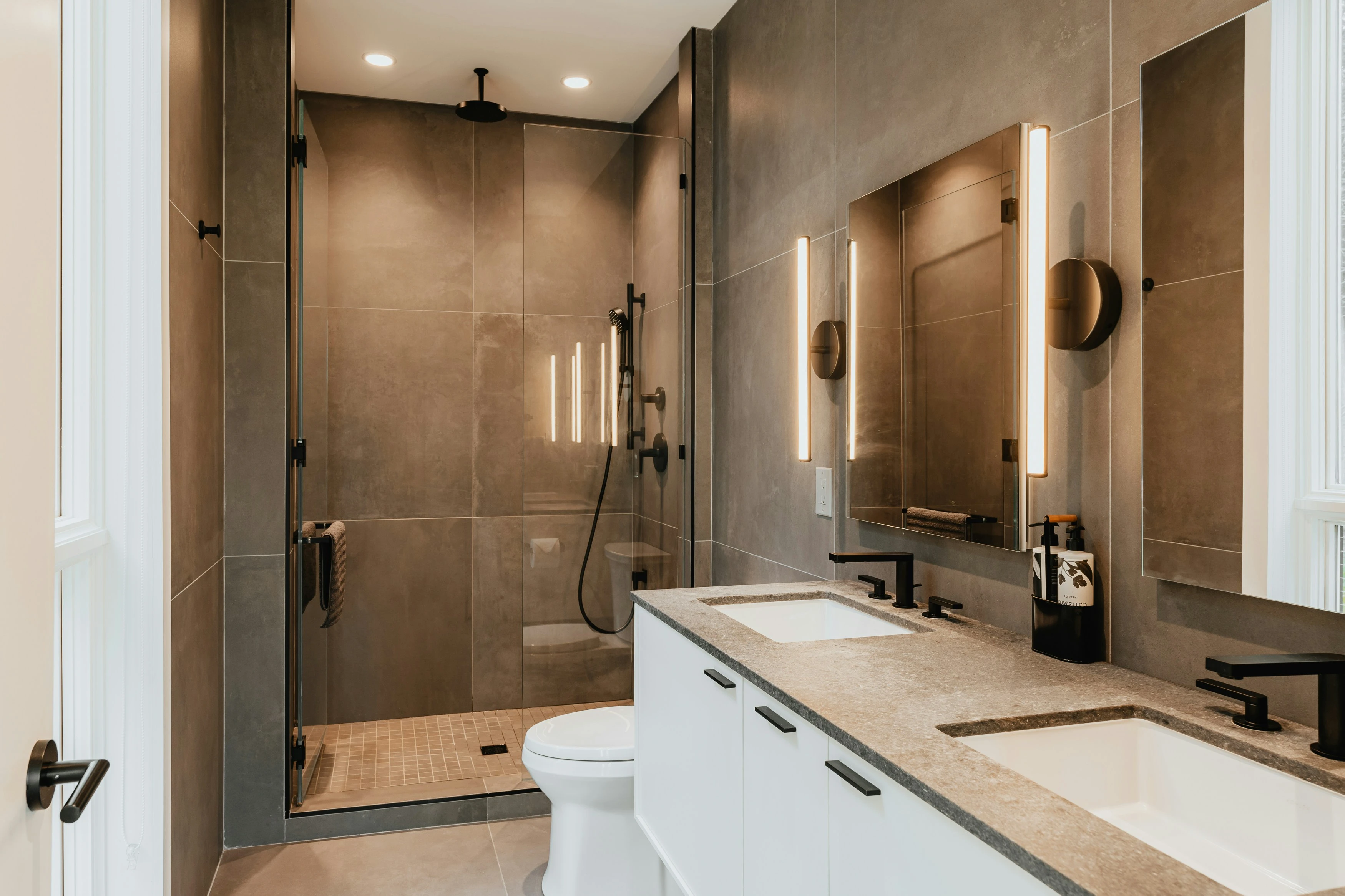 Bathroom with a black single-lever basin mixer, a wide mirror and a glass shower