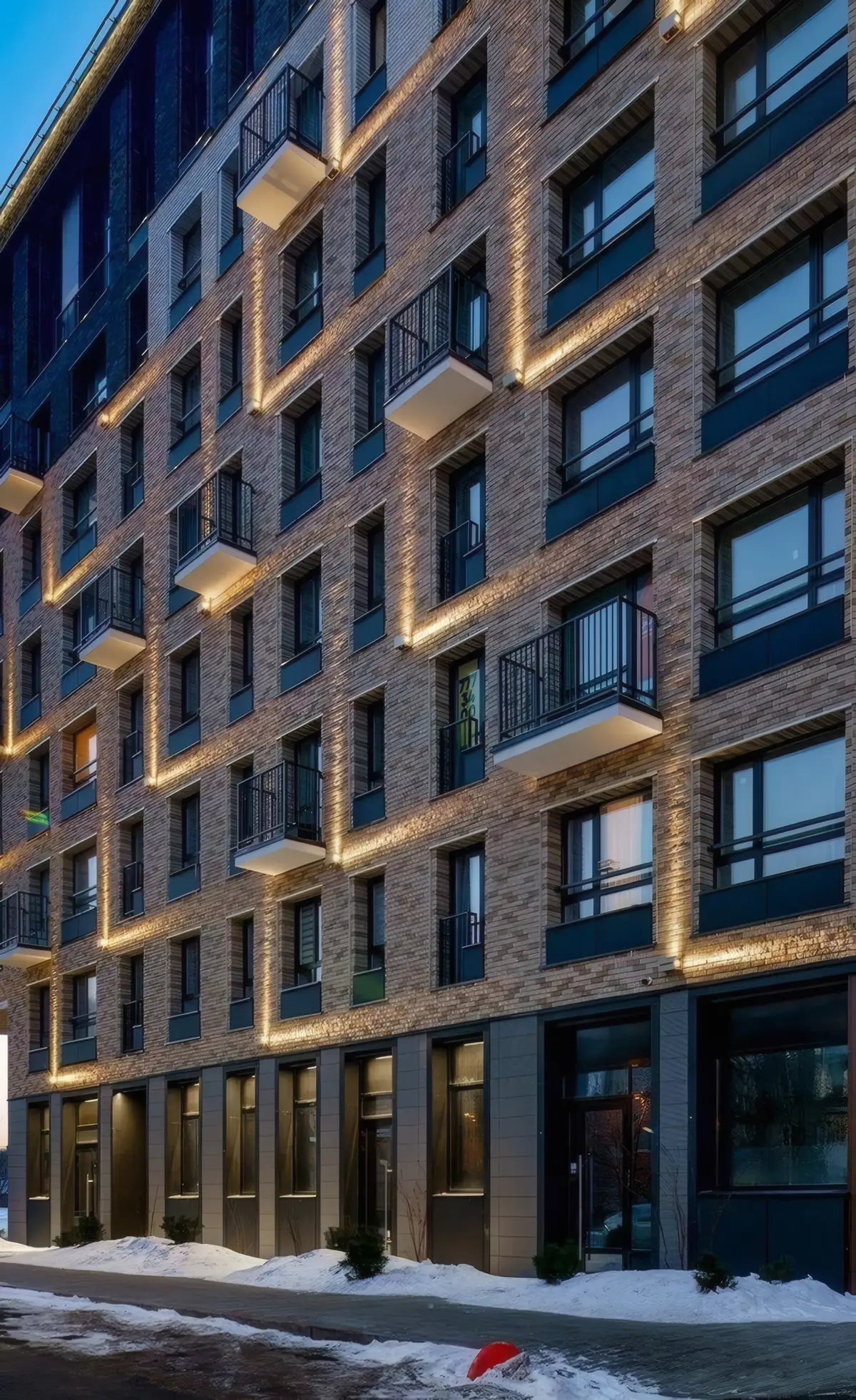 Brick apartment block at dusk with every window framed by warm light